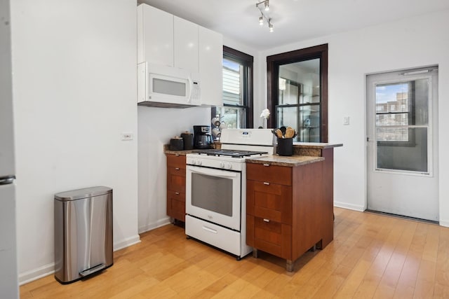 kitchen with white appliances, light hardwood / wood-style floors, and white cabinetry