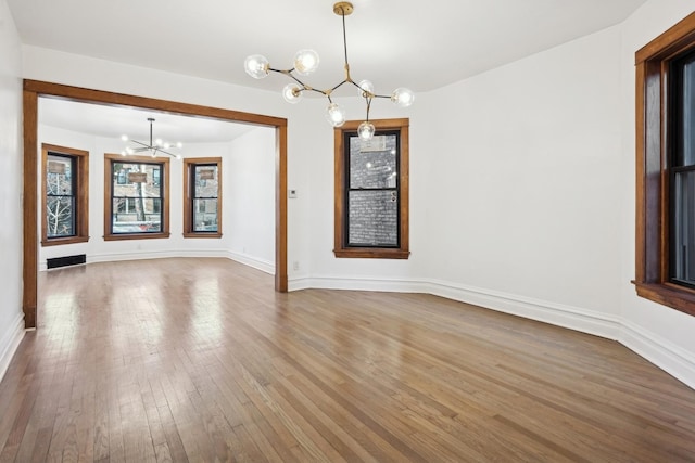 unfurnished dining area featuring a chandelier and wood-type flooring