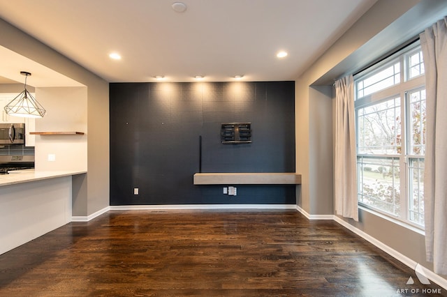 unfurnished living room featuring dark wood-type flooring and a healthy amount of sunlight