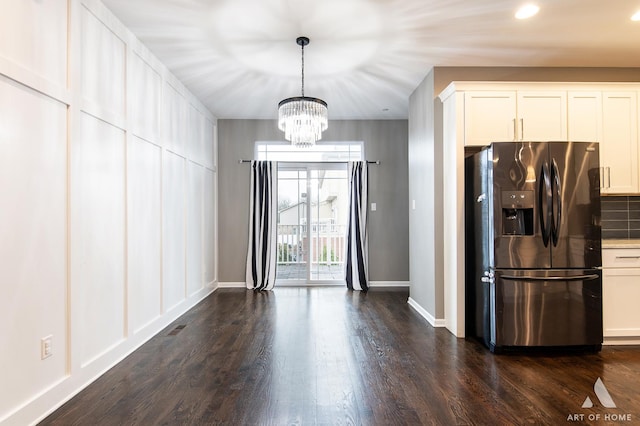 kitchen featuring stainless steel fridge, white cabinets, decorative light fixtures, and a notable chandelier