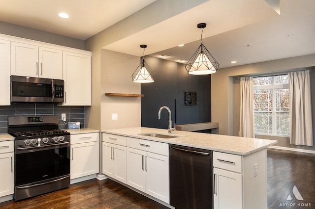 kitchen with sink, stainless steel appliances, kitchen peninsula, pendant lighting, and white cabinets