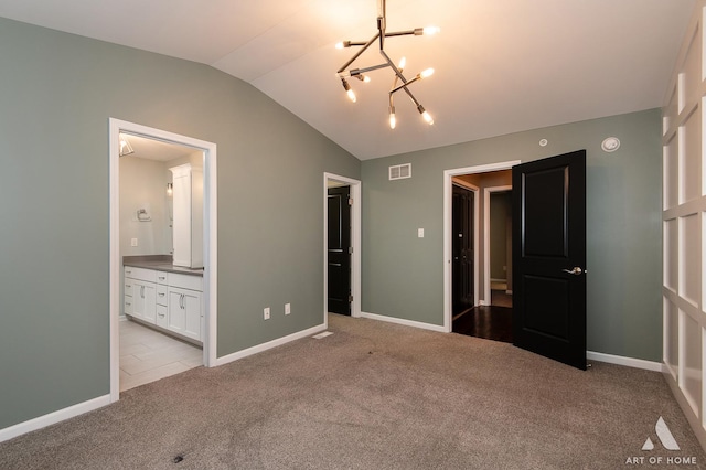 unfurnished bedroom with ensuite bath, light carpet, a chandelier, and vaulted ceiling