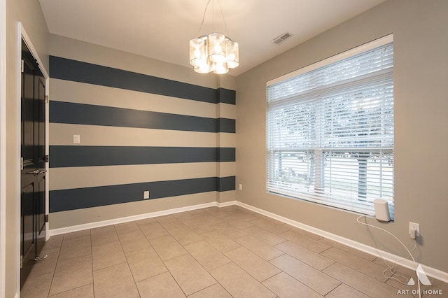 spare room with a chandelier, tile patterned flooring, and plenty of natural light