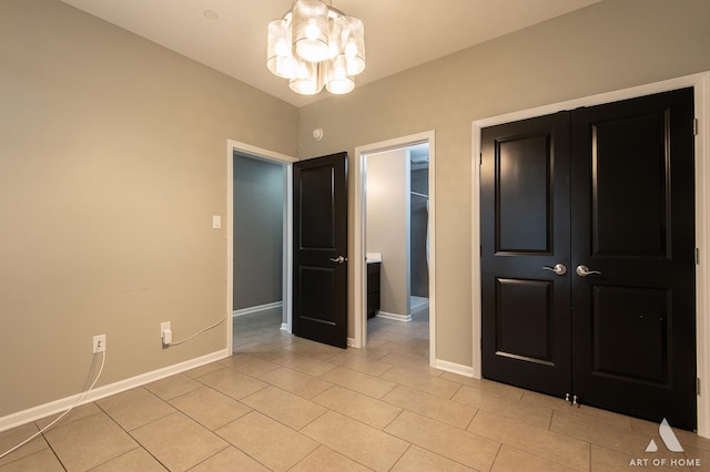 unfurnished bedroom featuring an inviting chandelier, a closet, and light tile patterned flooring