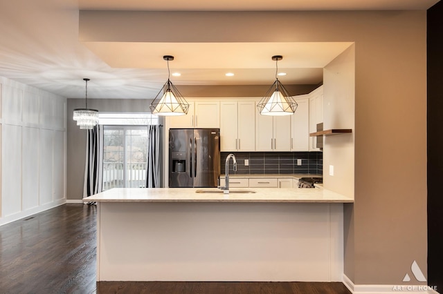 kitchen featuring sink, stainless steel refrigerator with ice dispenser, backsplash, decorative light fixtures, and white cabinets