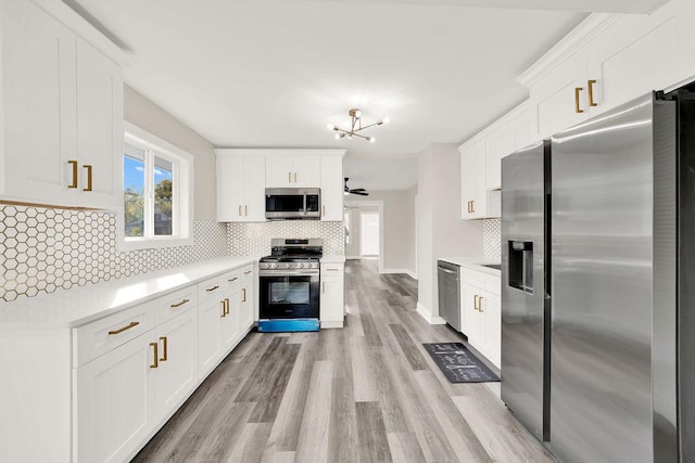 kitchen with decorative backsplash, ceiling fan with notable chandelier, stainless steel appliances, light hardwood / wood-style flooring, and white cabinetry