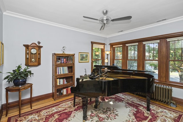 misc room featuring ceiling fan, light wood-type flooring, crown molding, and radiator