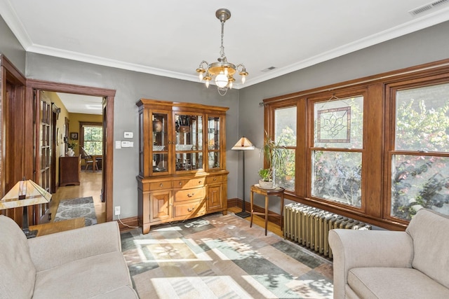 living area with radiator heating unit, hardwood / wood-style flooring, crown molding, and a notable chandelier