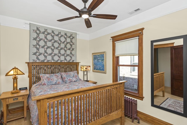 bedroom with ceiling fan, radiator heating unit, and light hardwood / wood-style flooring