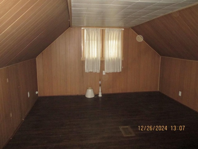 additional living space with wood walls, dark wood-type flooring, and vaulted ceiling