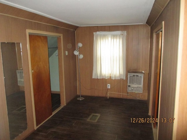 interior space with dark hardwood / wood-style floors, wood walls, and heating unit