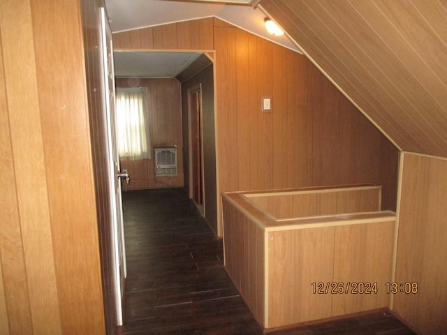 hallway with heating unit, wood walls, dark hardwood / wood-style flooring, and lofted ceiling