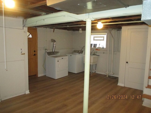 basement featuring separate washer and dryer, sink, and dark hardwood / wood-style floors