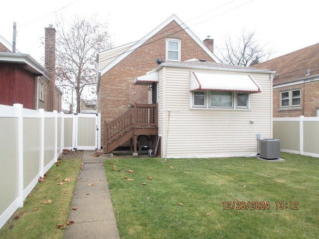 back of property with a yard and central AC