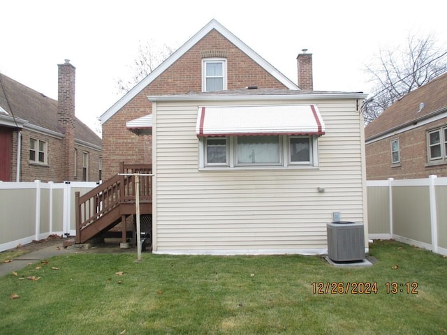 back of house featuring a lawn and central air condition unit