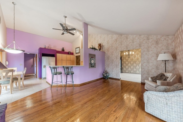 living room with ceiling fan, light wood-type flooring, and lofted ceiling