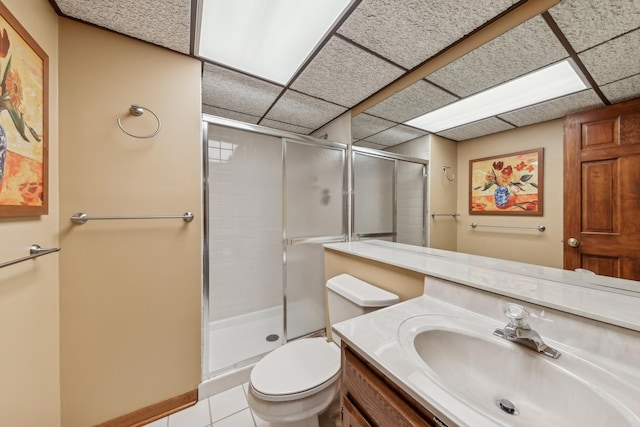 bathroom featuring a drop ceiling, vanity, tile patterned flooring, toilet, and a shower with shower door