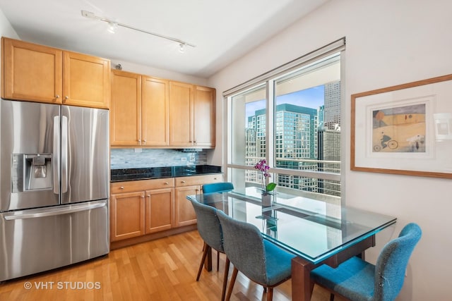 kitchen featuring stainless steel fridge with ice dispenser, rail lighting, light hardwood / wood-style floors, decorative backsplash, and light brown cabinetry