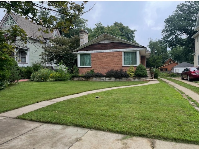 view of front of property featuring brick siding, a chimney, and a front lawn