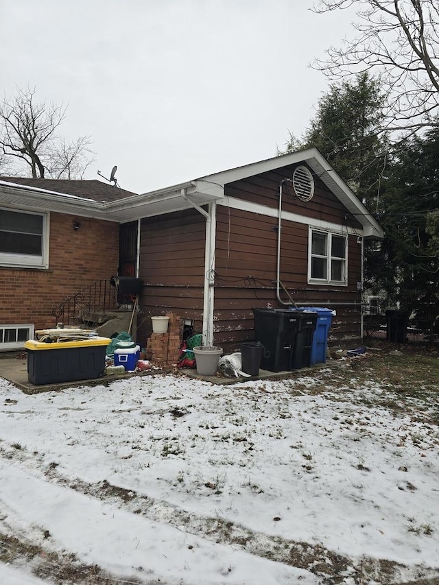 view of snowy exterior featuring brick siding