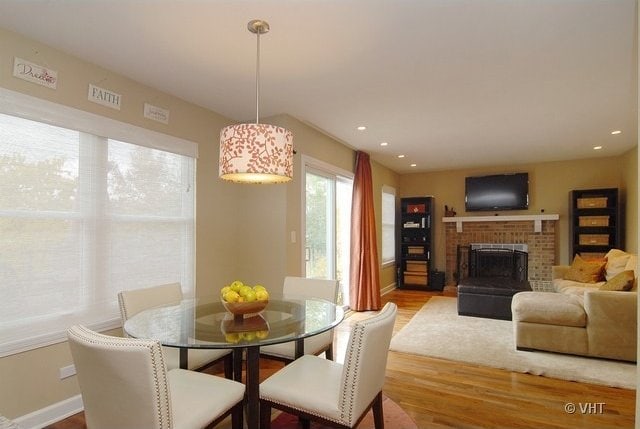 dining space featuring hardwood / wood-style floors and a brick fireplace