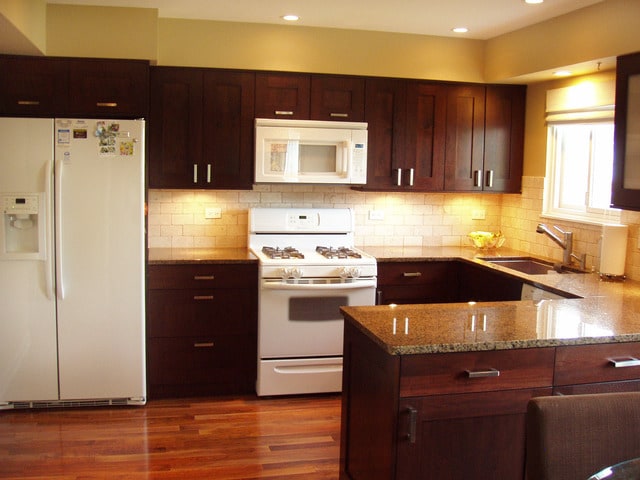 kitchen featuring light stone countertops, backsplash, white appliances, dark wood-type flooring, and sink