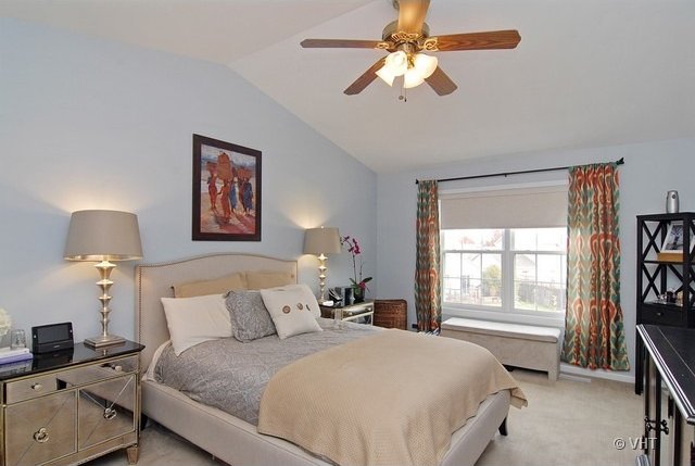 carpeted bedroom featuring ceiling fan, lofted ceiling, and radiator