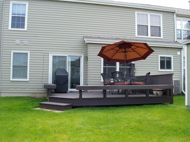 back of property featuring a lawn, cooling unit, and a deck