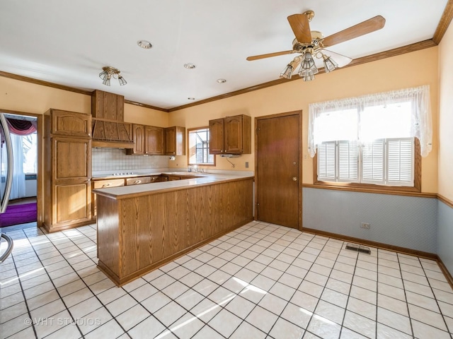 kitchen with ceiling fan, kitchen peninsula, backsplash, and crown molding