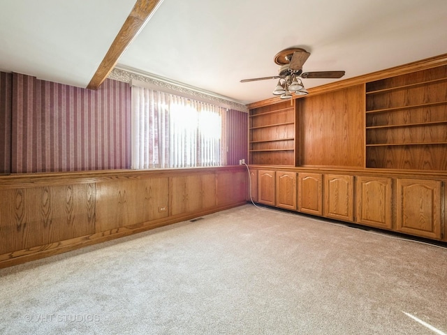 carpeted empty room with ceiling fan and built in shelves