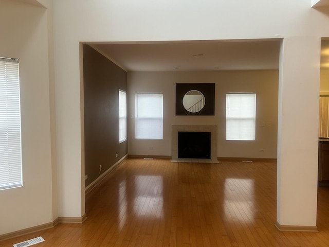 unfurnished living room featuring a tiled fireplace and light hardwood / wood-style floors