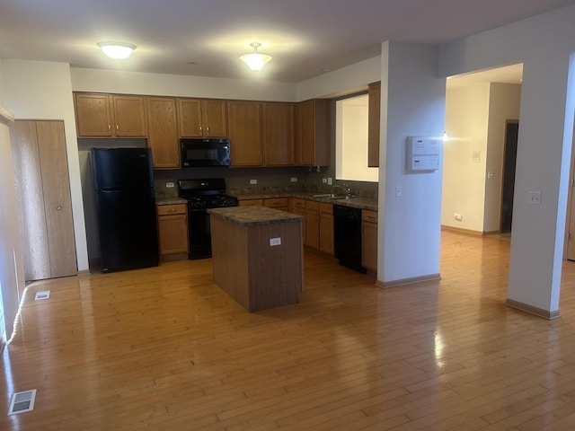 kitchen featuring light hardwood / wood-style floors, sink, black appliances, and a kitchen island