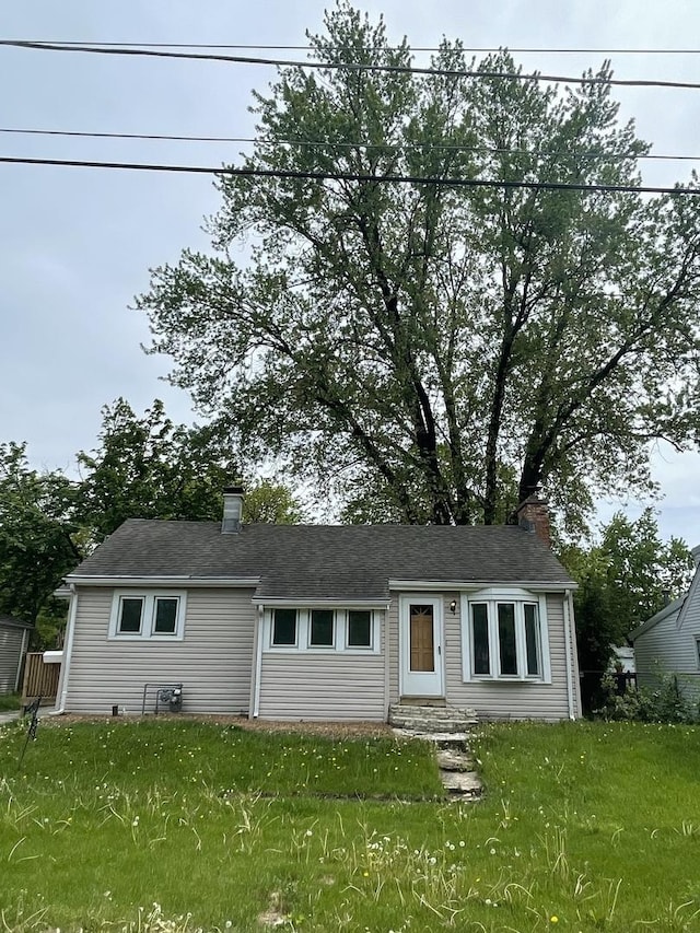 single story home with entry steps, a chimney, and a front yard