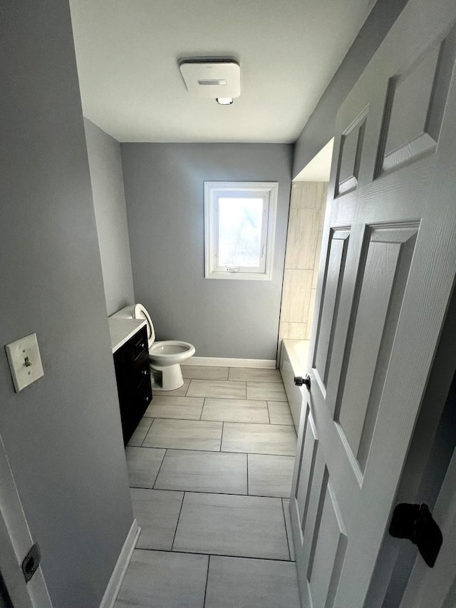 full bath featuring a tub, baseboards, vanity, and toilet