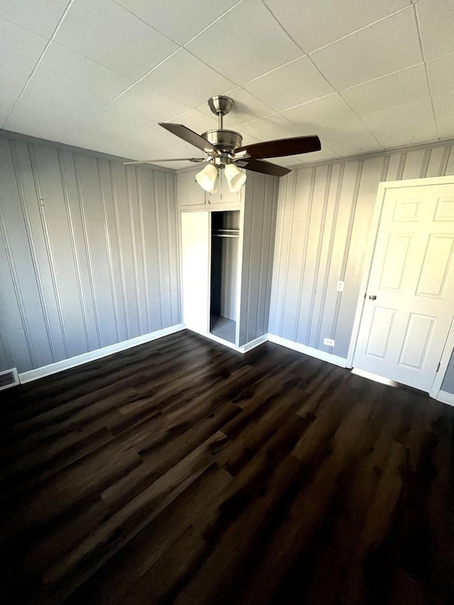 unfurnished bedroom with dark wood-type flooring, visible vents, baseboards, and a ceiling fan