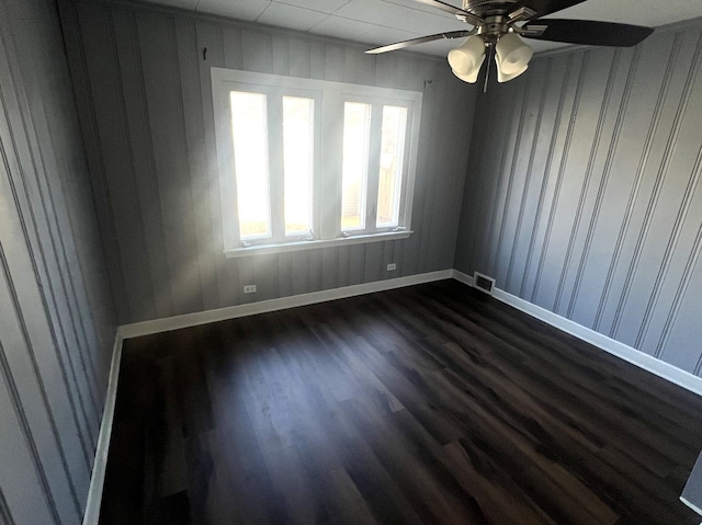 unfurnished room featuring ceiling fan, dark wood finished floors, visible vents, and baseboards