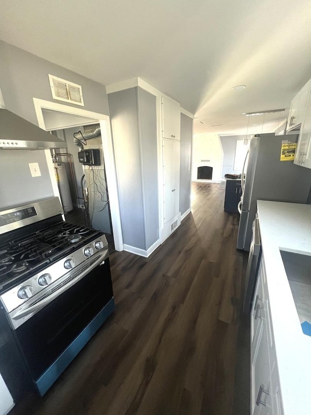 kitchen with dark wood-style flooring, stainless steel appliances, light countertops, visible vents, and white cabinets