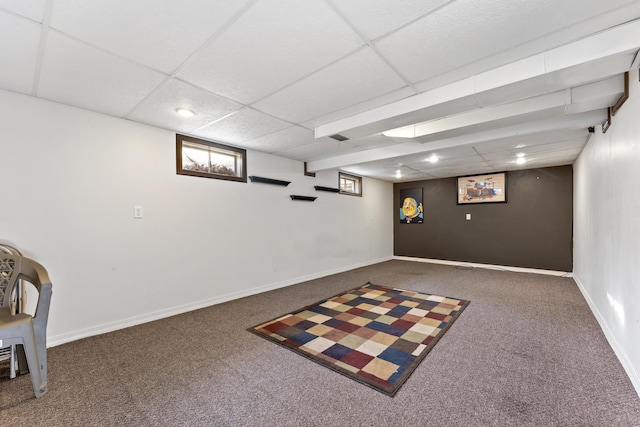 basement with a paneled ceiling and dark colored carpet