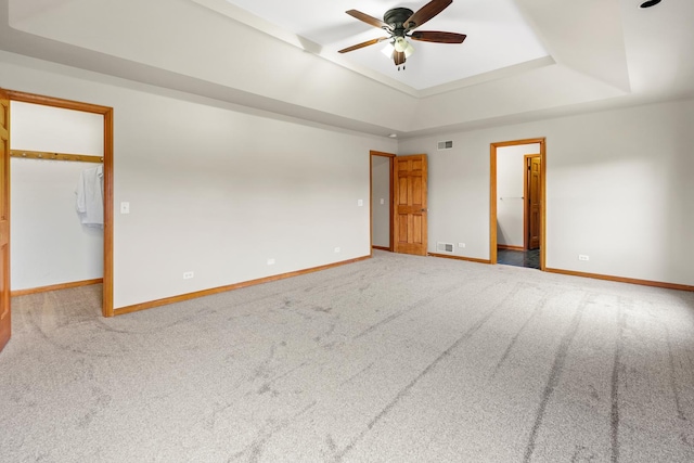 carpeted spare room with a tray ceiling and ceiling fan