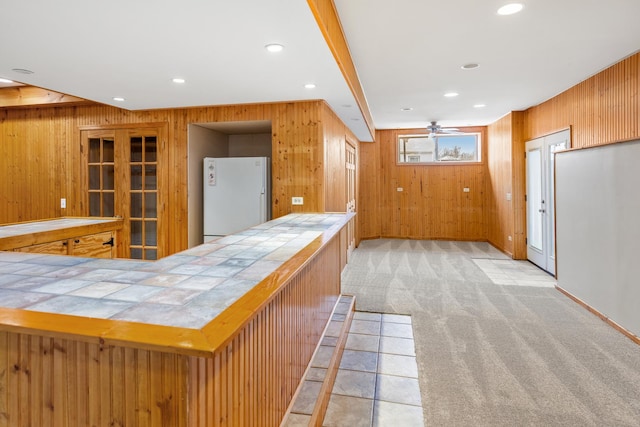 bar featuring ceiling fan, tile counters, light colored carpet, and white refrigerator