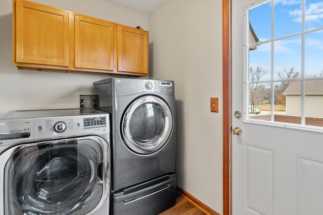 washroom featuring washing machine and clothes dryer, hardwood / wood-style floors, and cabinets