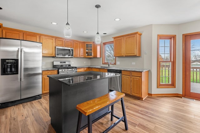 kitchen with dark stone counters, a wealth of natural light, a kitchen island, and stainless steel appliances