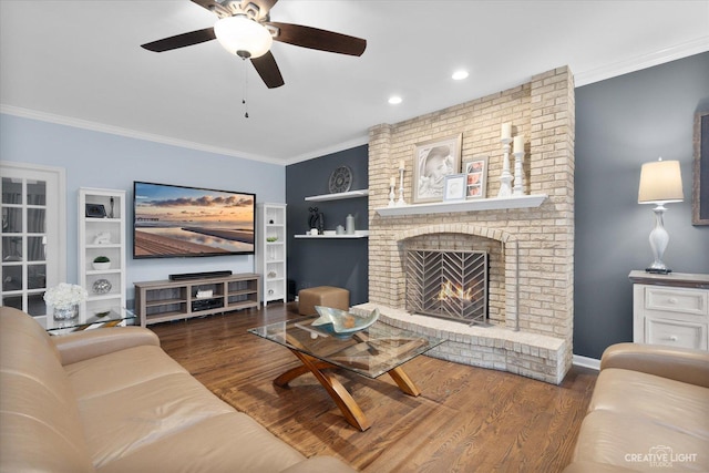 living room featuring a fireplace, ornamental molding, ceiling fan, and dark wood-type flooring