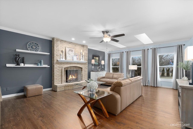 living room with ceiling fan, a skylight, a fireplace, and wood-type flooring