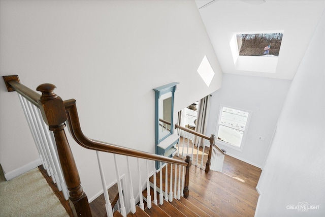 stairway featuring a towering ceiling and a skylight