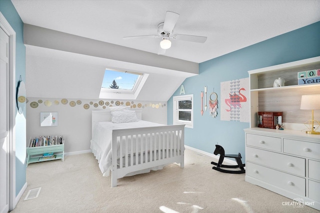 carpeted bedroom featuring ceiling fan, a textured ceiling, and vaulted ceiling with skylight