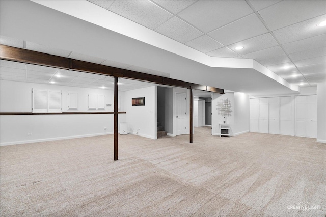 basement with a drop ceiling and light colored carpet