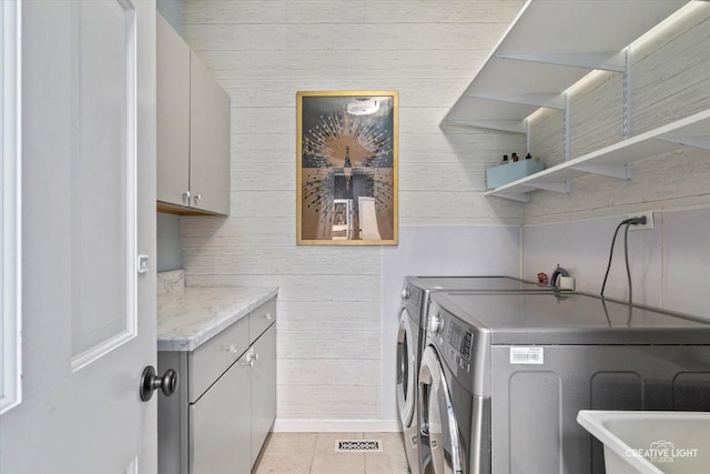 washroom with cabinets, washing machine and clothes dryer, and light tile patterned floors