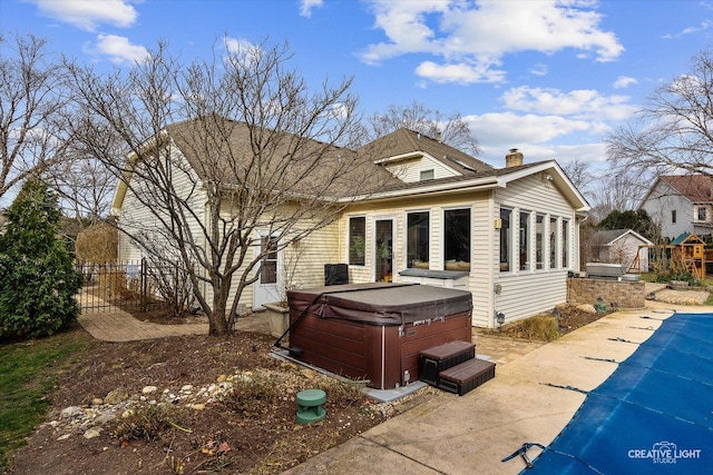 rear view of property with a swimming pool with hot tub and a patio area