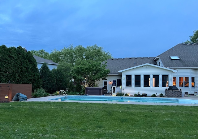 back of house featuring a pool with hot tub and a yard